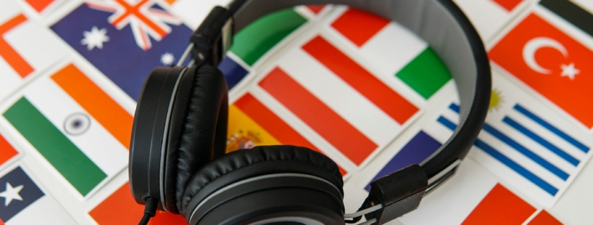 Learning foreign languages online. Headphones and countries flags on the background.